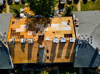 A worker replace shingles on the roof of a home repairing the roof of home